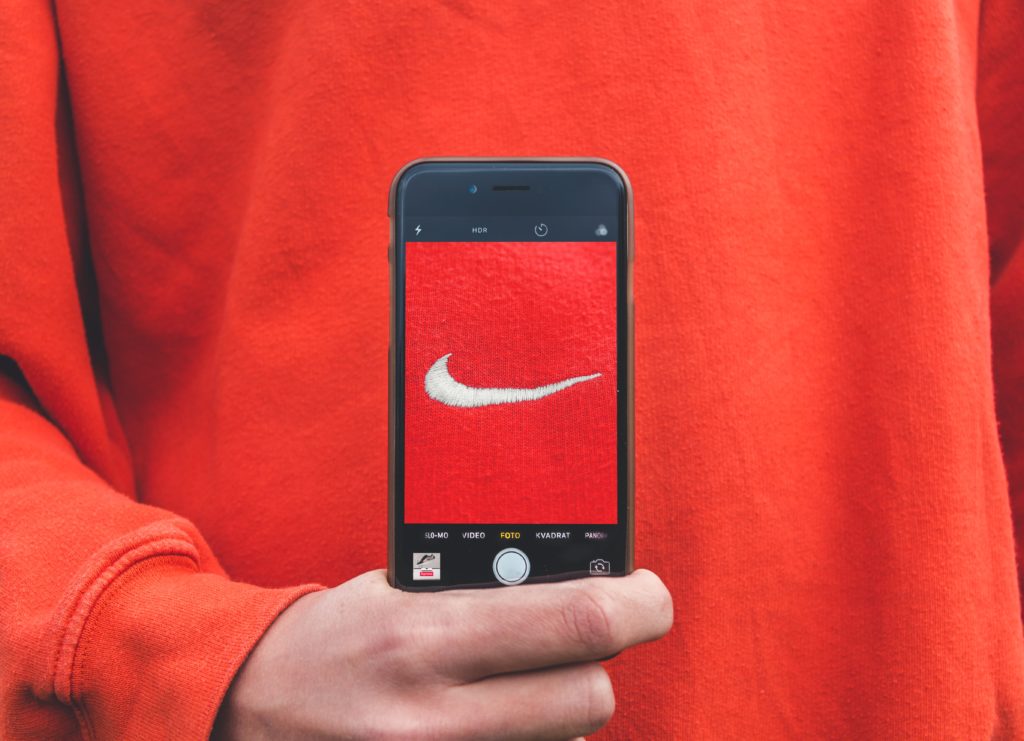 Person wearing Nike sweatshirt holding an iPhone